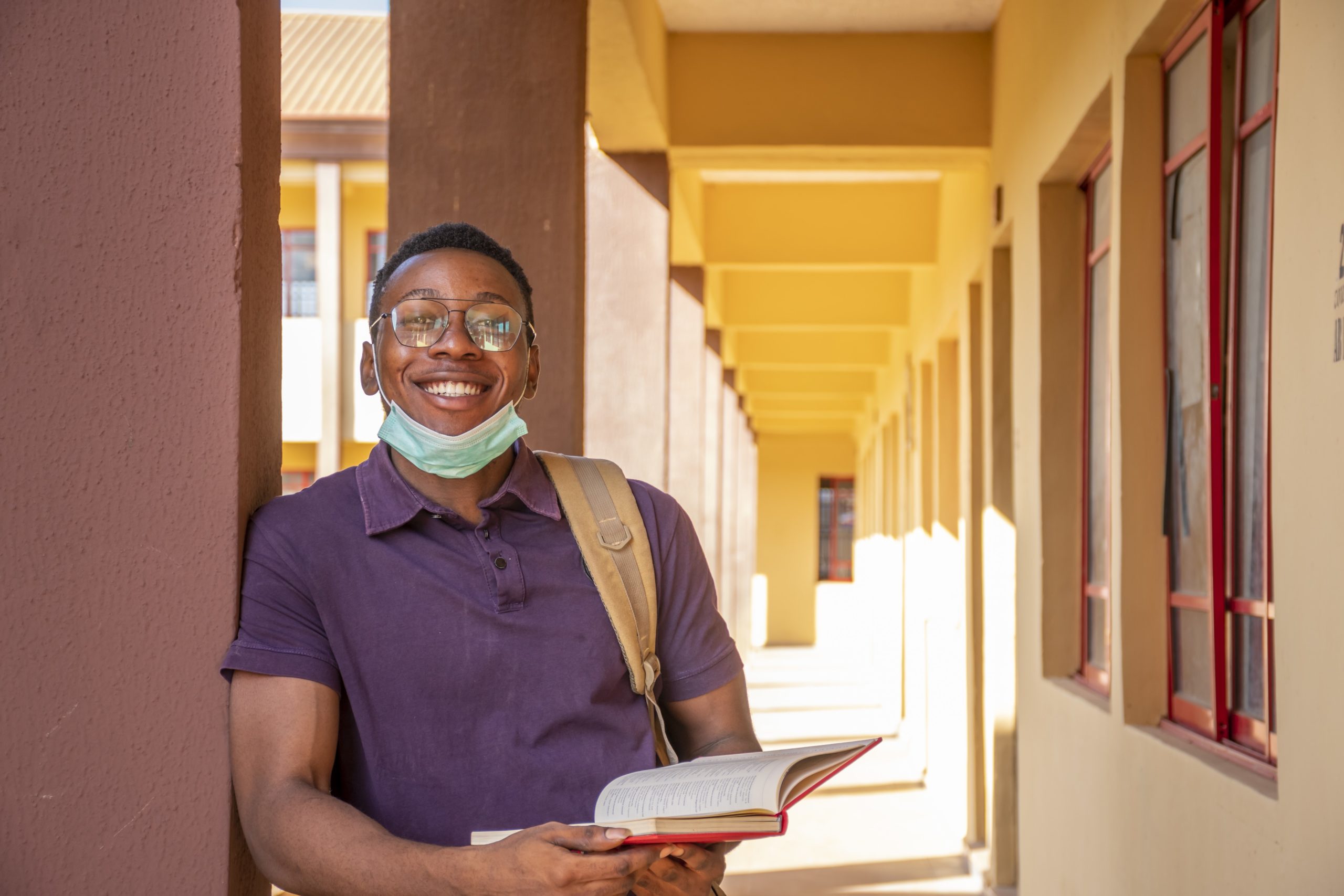 A portrait of a smiling African male student holding a book and smiling